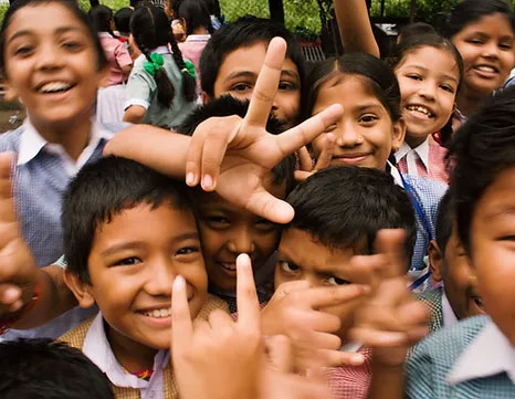 Photo of group of children smiling and showing peace hand gesture