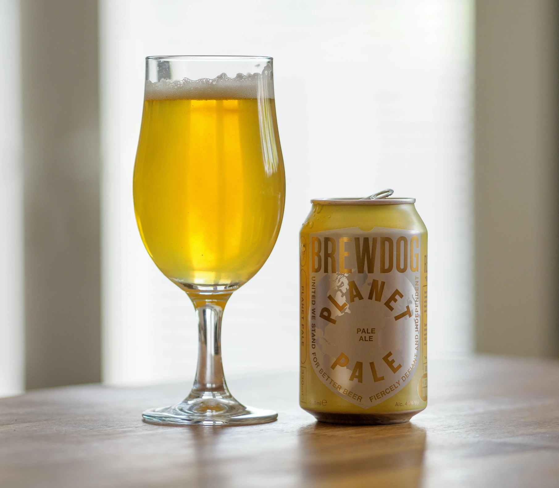 A beer glass full containing a BrewDog beer, next to a BrewDog can