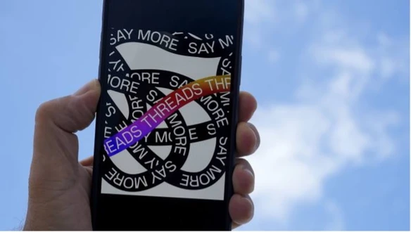 Person holding mobile phone with image of Threads logo showing